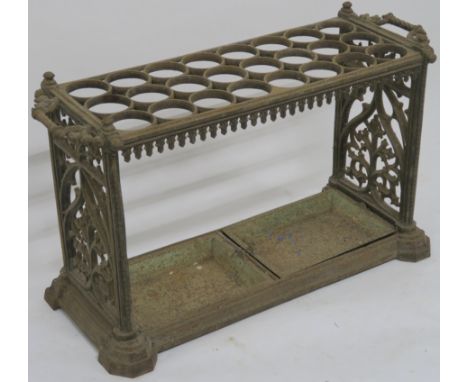 A VICTORIAN CAST IRON STICK STAND with twenty four circular divisions, above a pair of drip trays and flanked by a pair of ha