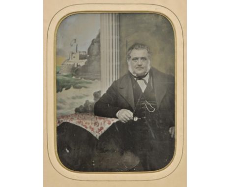 *Ambrotype. A full-plate hand-painted ambrotype of an unidentified man, circa 1870,  the seated man in front of a view of a r