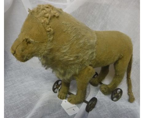 AN EARLY 20TH CENTURY PLUSH PUSH-ALONG LION, possibly Steiff on cast-iron four-spoke gilt painted wheels