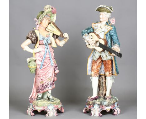 A very large pair of Continental pottery figures, first half 20th century, dressed in Regency style clothing, raised on elabo