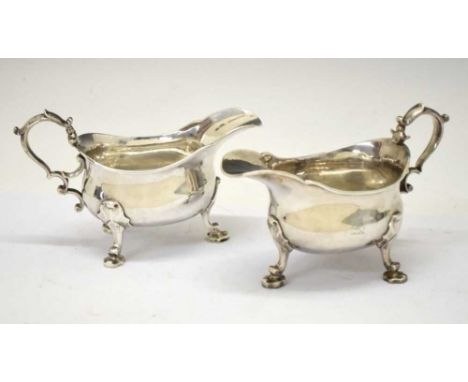 Pair of George II silver sauceboats having scroll handles and each standing on three leaf-capped elaborate pad feet, sponsors