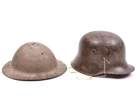 A WWI Brodies pattern steel helmet, and a German M1916 helmet. Both in excavated condition. (2) 