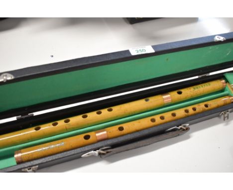 A cased pair of Chinese bamboo flutes, text translates as Suzhou National Musical Instrument