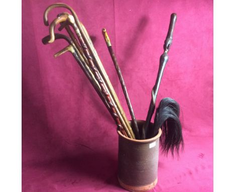 An earthenware stick stand and contents of various walking sticks