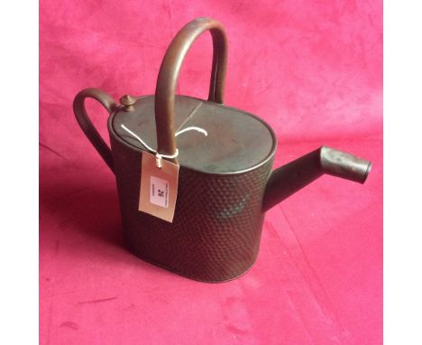 A vintage copper watering can having spot hammered decoration
