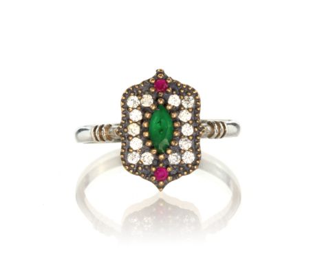 A jewelled silver dress ring set with a green marquise cut gemstone, flanked by two round cut rubies and a border of round cu