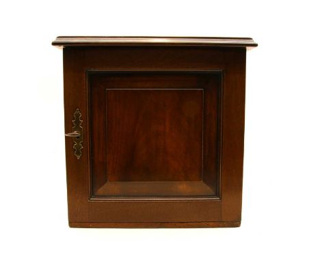 A George III mahogany spice cupboard, a fielded panel door, enclosing seven small drawers with brass ring handles, a brass mo