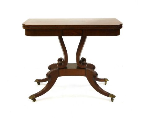 A Regency strung mahogany fold-over card table, on scrolled supports and outswept legs with cast brass lion's mask castors, 9