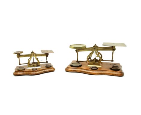 An oak and brass postal scale, with a selection of weights and ivorine 'Inland Postal Rates' label, 29cm wide and another sma