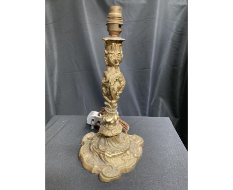 A GILT METAL ORMOLU TABLE LAMP, the column with foliate C-scrolls to a conforming tri-form base, fitted for electricity. 29.5