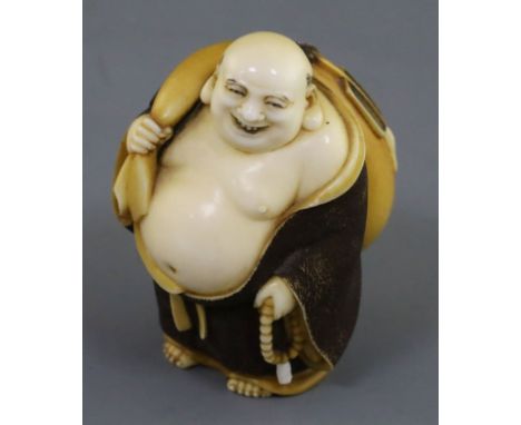 A Japanese ivory okimono netsuke of Hotei, early 20th century, standing and holding a rosary and his sack of wind, red lacque