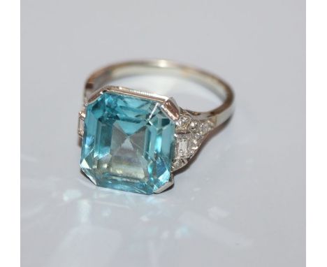 A white metal and blue zircon ring with diamond set shoulders (stone chip), size K.