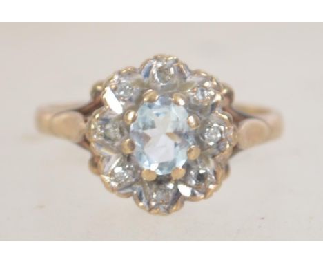 A hallmarked 9ct gold and diamond ring set with a central aquamarine surrounded by illusion set diamonds. Hallmarked Birmingh