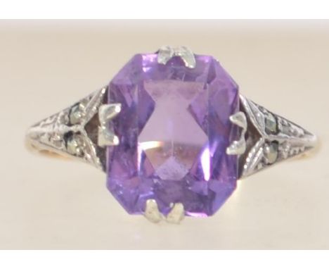 An Art Deco 9ct gold and silver ring set with a large purple faceted stone with marcasite set shoulders.  Marked 9ct and Sil.