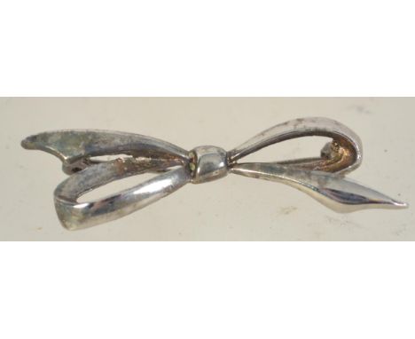 A silver brooch in the form of a bow with roller clip clasp. Marked Silver. Measures 2 1/4 inches.