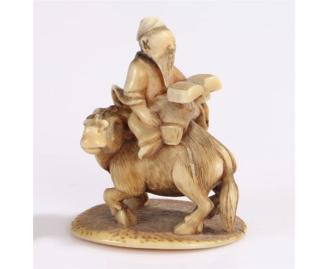 Japanese Edo period ivory okimono, in the netsuke style, the miniature okimono with a figure reading a book seated upon a goa