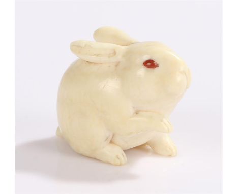 Japanese Edo period ivory and coral netsuke, carved as a rabbit with on foot raised, inset coral eyes, possibly Kyoto school