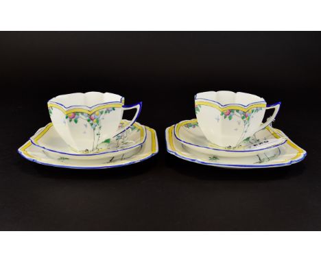 A Pair Of Shelley Art Deco Queen Anne Trios Two in total each comprising charger, saucer and cup, each in yellow, blue, and g