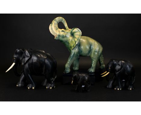 A Collection Of Elephant Figurines Four in total to include descending size carved ebonised wood and one large ceramic Elepha