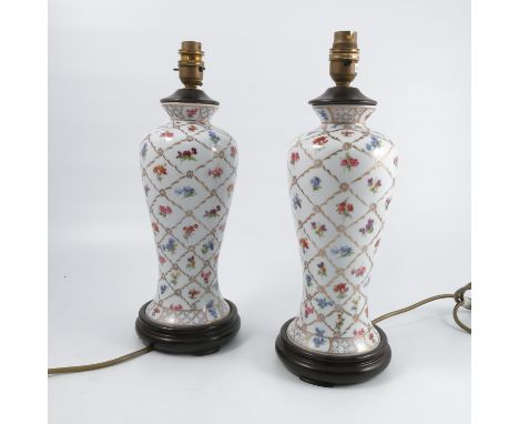 A pair of porcelain lamp bases, of baluster form, decorated with flowers and gilt to a white ground, height 16ins excluding s