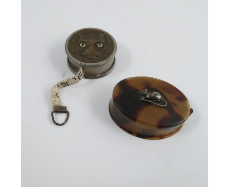 A circular tape measure, the top decorated with a portrait of a cat with green glass eyes, together with an oval tortoiseshel