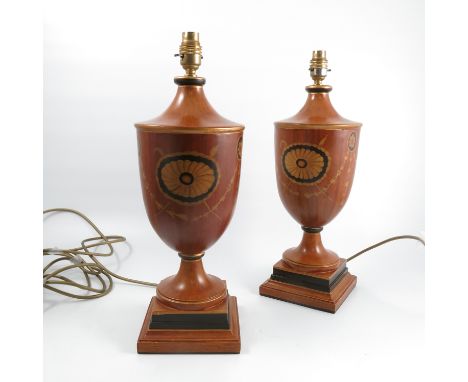 A pair of wooden lamp bases, of urn form, decorated with roundels and swags, raised on a pedestal to a stepped square base, h