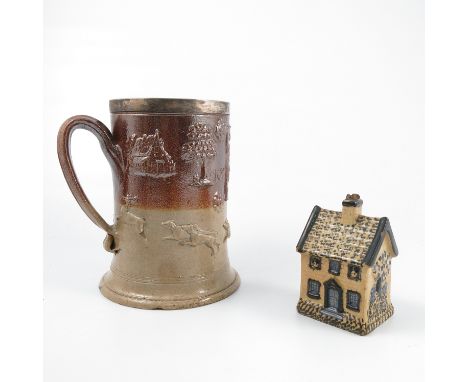 An 18th century stoneware flagon, decorated with a plaque of an interior scene with figures seated at a table, surrounded by 