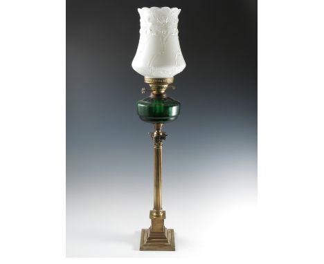 A Duplex oil lamp, the green glass oil reserve raised on a corinthain column on a stepped square base, the white glass shade 