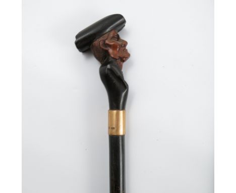 A 19th century walking stick, the carved handle formed as a man wearing a hat, with gold coloured colour and banded shaft, he