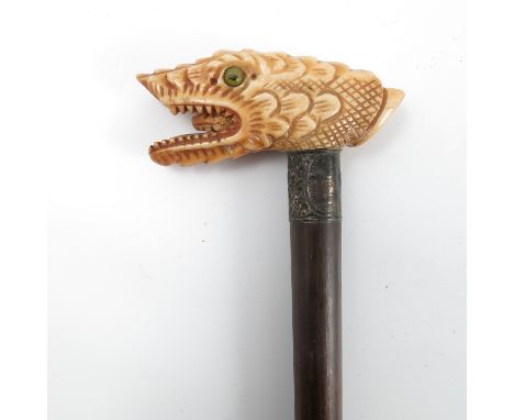 A 19th century walking stick, the carved ivory handle formed as the mask of a mythical beast, height 35ins