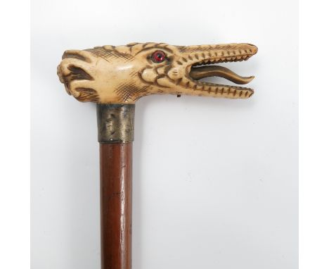 A 19th century walking stick, the carved ivory handle formed as the mask of a mythical beast, height 33.5ins