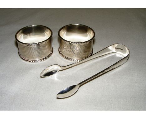 A pair of sterling silver napkin rings, each engine turned & hallmarked for Birmingham & a pair of sterling silver sugar tong
