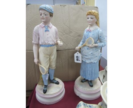 A Pair of Late XIX Century Continental Bisque Figures, a young boy holding a tennis racquet and ball and a young girl holding