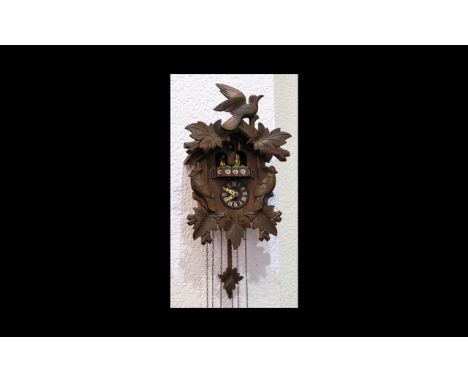 A German Black Forest Cuckoo Clock Of traditional form, triple weighted with Eidelweiss painted decoration and figures to top