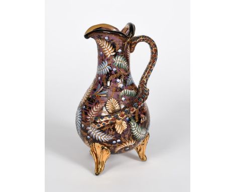 A Moser enamelled amethyst glass ewer, on three foliate feet, with applied reptile handle, enamelled in colours and gilt with