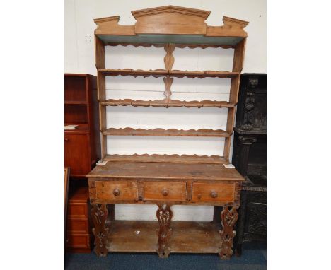 A pine dresser, the broken arch pediment above a four shelf Delft rack, over three drawers raised on fret work supports unite