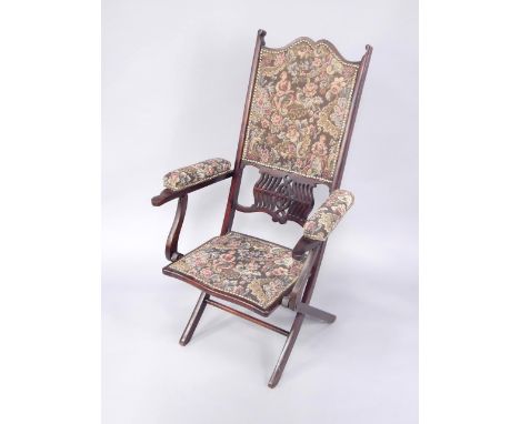 A Victorian folding beech campaign or steamer chair, with overstuffed tapestry seat, back and arm rests.