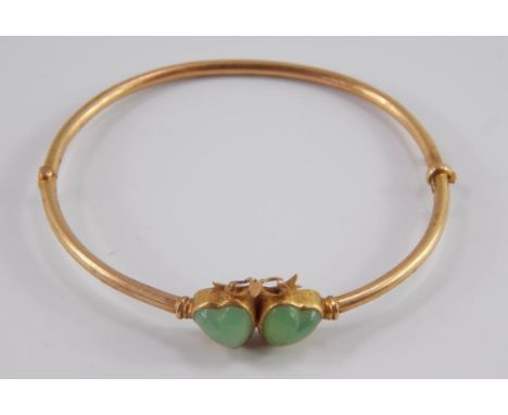A Victorian jade set double heart bangle, set in yellow metal on a snap clasp, marked 15, 6.8g.