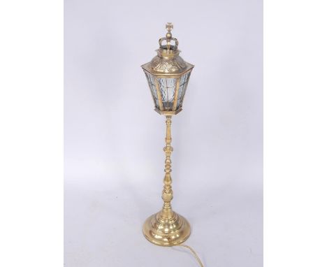 A brass table lamp, the hexagonal lantern top with crown surmount, inset textured glass panels, raised on a turned column and