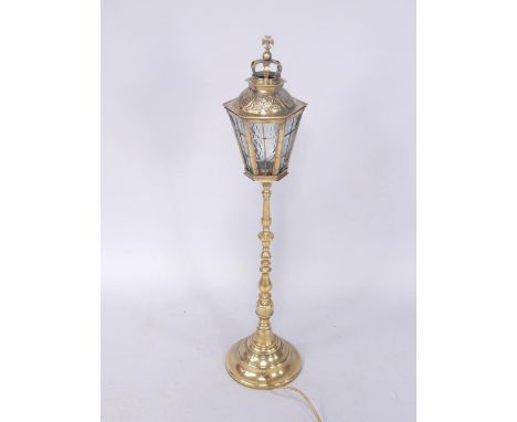 A brass table lamp, the hexagonal lantern top with crown surmount, inset textured glass panels, raised on a turned column and