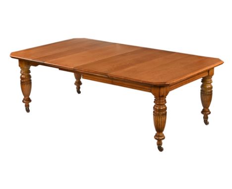 A Victorian light oak extending dining table, with two leaves and raised on bulbous turned and fluted legs terminating in bra