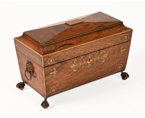 A 19th century rosewood and brass inlaid sarcophagus shaped tea caddy, raised on claw and ball feet with lion mask handles to