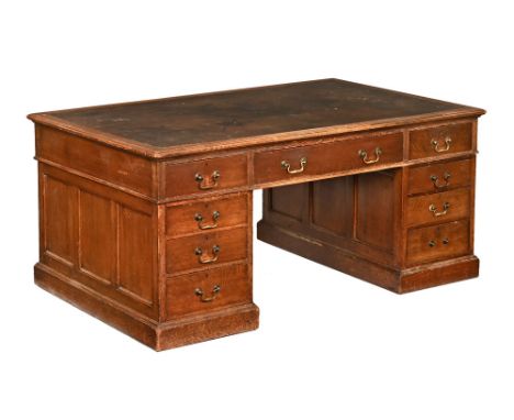 A late 19th/early 20th century oak partners desk, with dark green leather tooled top and having a long central drawer and fou