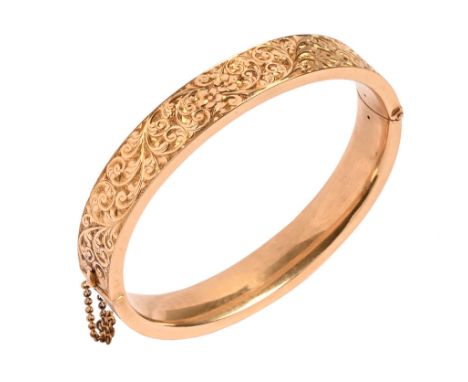 An 18 ct yellow gold foliate engraved hinged bangle, with safety chain.  37.19 grams (see illustration).