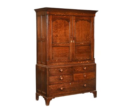A George III oak press cupboard, in two sections the top half with moulded cornice above a pair of panelled doors opening to 