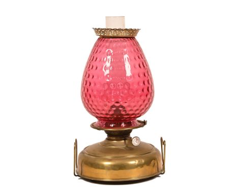 A late 19th/early 20th century brass oil lamp, with cranberry glass shade.  Height including chimney 50 cm.