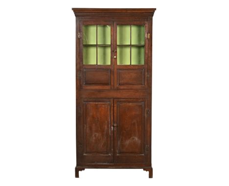 A Georgian oak cupboard, the cornice with diamond decoration above a pair of glazed and panelled doors opening to two interna