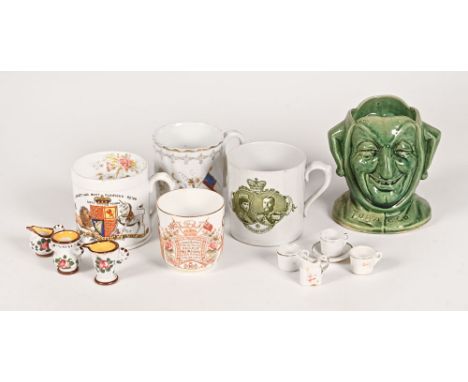 A collection of three commemorative mugs, a cup, a jester tobacco jar and a collection of Wemyss style miniatures.  Tallest 1