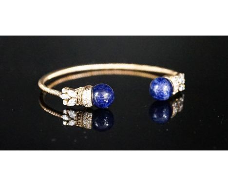 A modern yellow metal twist, two stone sodalite? and diamond set open bangle, gross weight 14 grams.