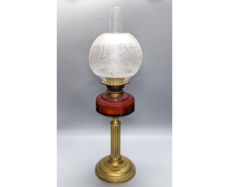 A Victorian brass oil lamp with etched glass shade and cranberry reservoir. 64cm total height